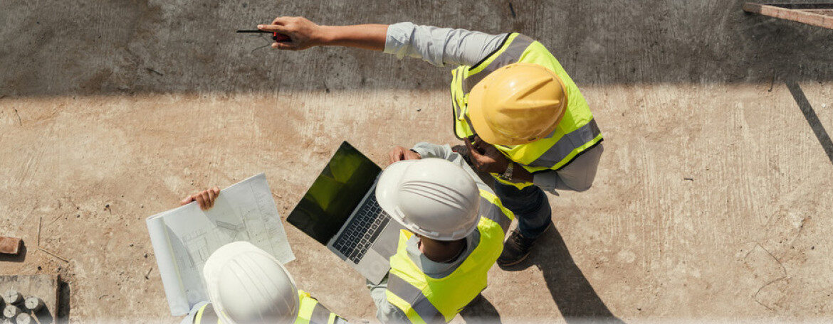 Zwei Bauleiter mit Helmen und Bauplan auf einer Baustelle
